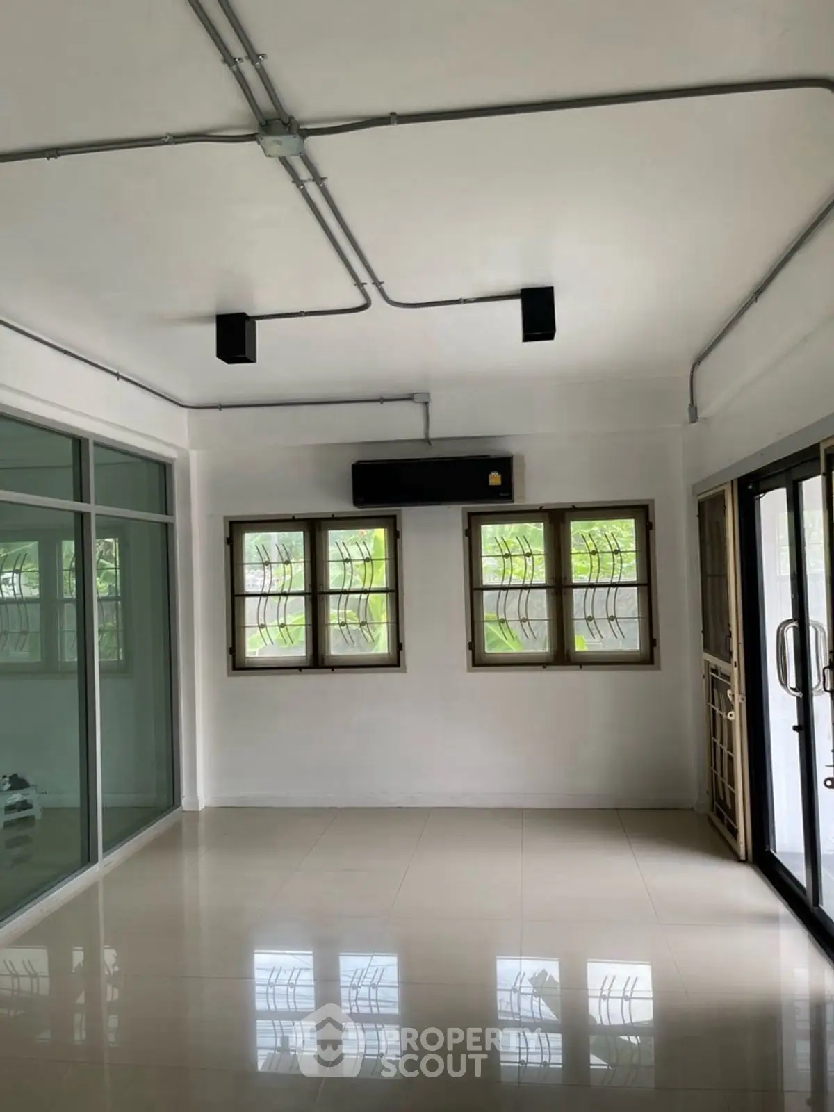 Spacious living room with large windows and modern lighting, perfect for natural light and comfort.
