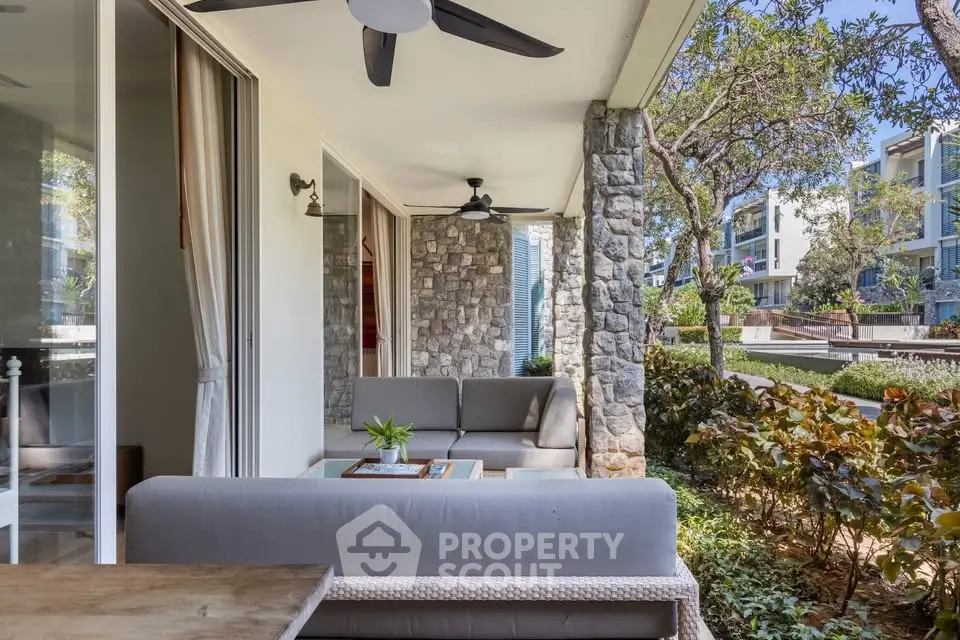 Charming outdoor patio with cozy seating and lush garden view in modern residential complex.