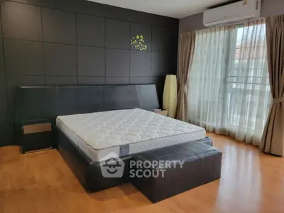 Spacious bedroom with modern decor and large window for natural light.