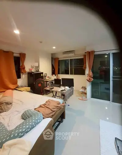 Spacious bedroom with city view and modern decor in high-rise apartment.