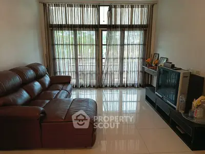 Spacious living room with leather sofa and large window offering natural light.
