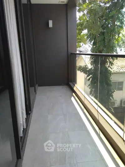 Spacious balcony with glass railing and scenic view, perfect for relaxation and enjoying the outdoors.