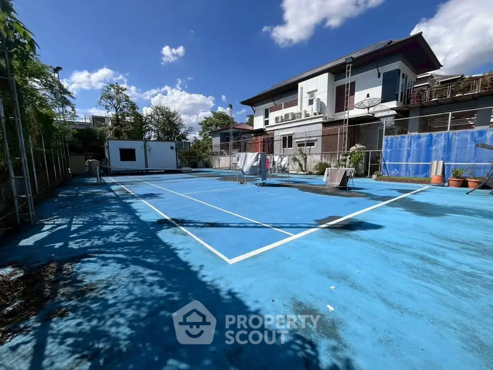 Spacious outdoor tennis court with clear blue sky and modern building backdrop.