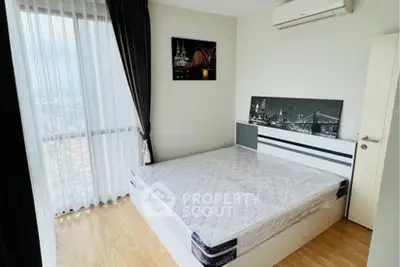 Modern bedroom with large window and city view, featuring stylish decor and air conditioning.
