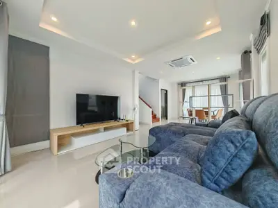 Spacious modern living room with plush seating and large TV, perfect for relaxation.