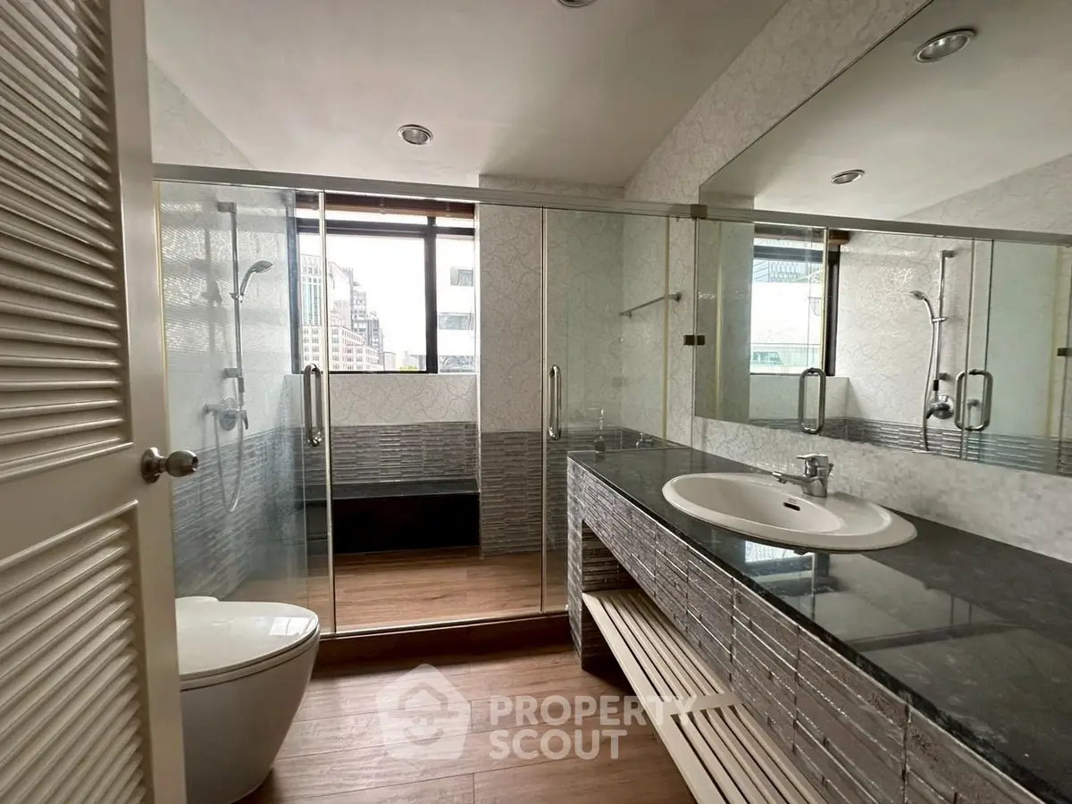 Modern bathroom with glass shower and sleek vanity in urban apartment