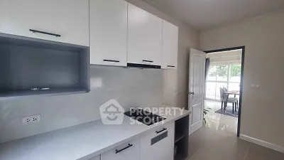 Modern kitchen with sleek cabinetry and gas stove, leading to a bright dining area.