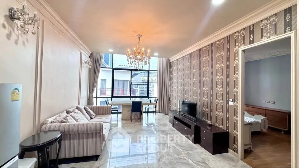 Luxurious living room with elegant chandelier and stylish decor, featuring a spacious layout and large windows.