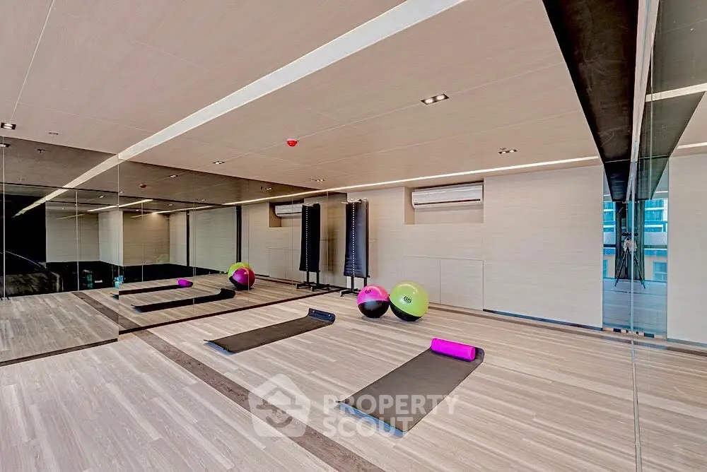 Modern gym with exercise mats and fitness balls in a sleek mirrored room.