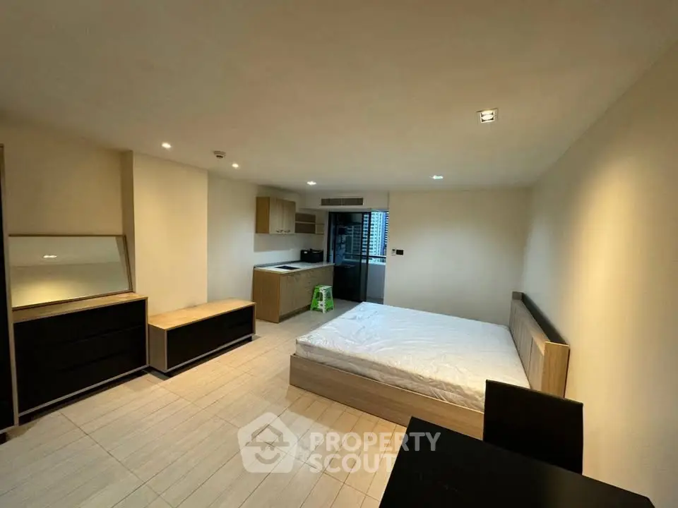 Spacious modern bedroom with minimalist design and kitchenette, ideal for urban living.
