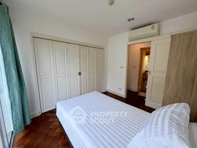 Spacious bedroom with built-in wardrobes and air conditioning in modern apartment.
