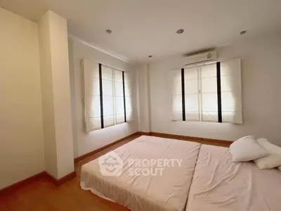 Spacious bedroom with natural light and minimalist decor, featuring a comfortable bed and wooden flooring.