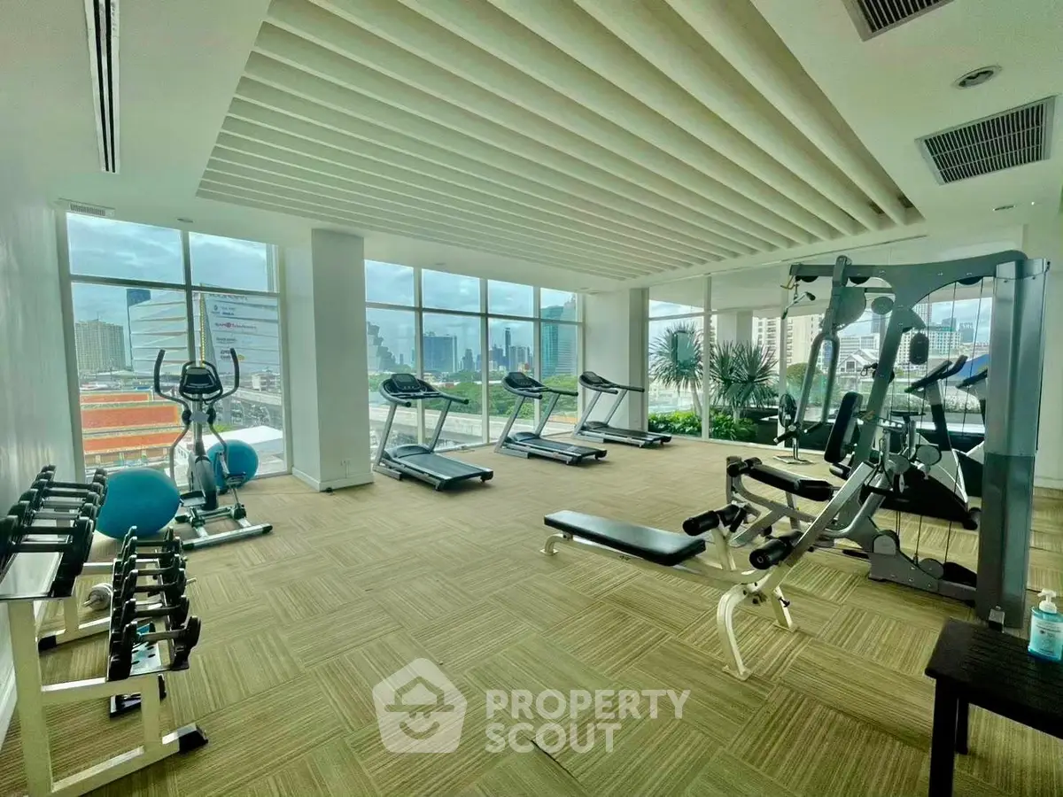 Spacious modern gym with city views and state-of-the-art equipment in luxury building.