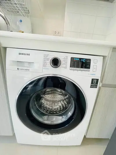 Modern Samsung washing machine in sleek kitchen setting with white cabinetry.