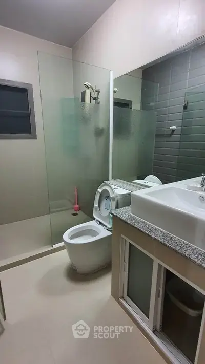 Modern bathroom with glass shower and sleek fixtures in contemporary home.