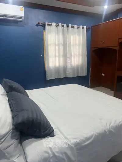 Cozy bedroom with blue accent wall and modern furnishings, perfect for relaxation.