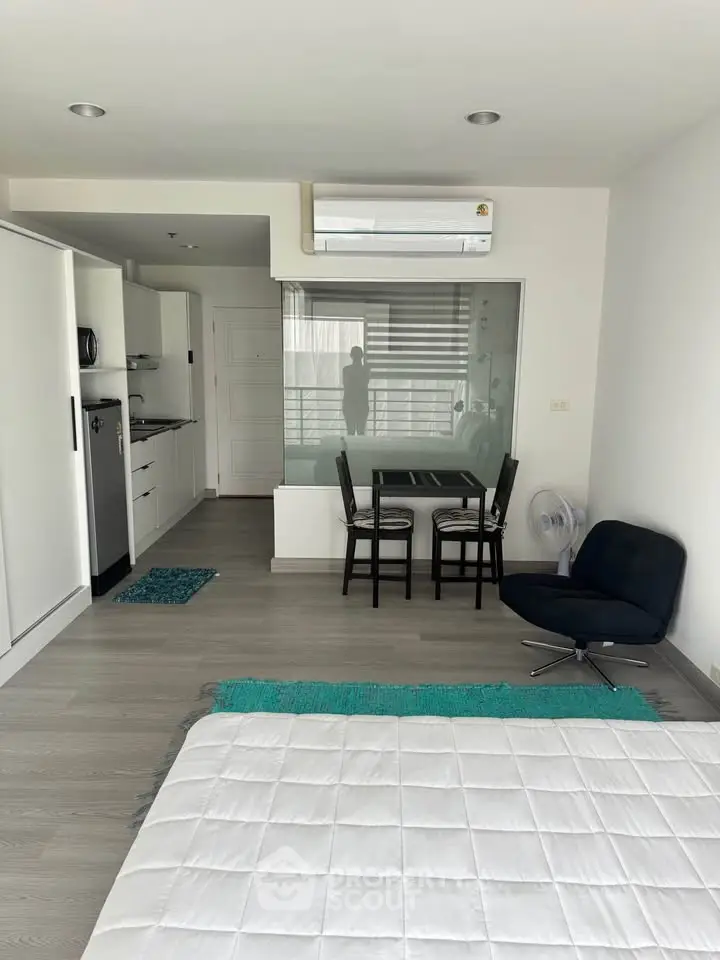 Modern studio apartment with open layout, featuring sleek kitchen and cozy dining area.