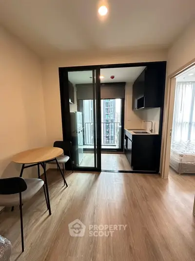 Modern apartment with open kitchen and dining area, featuring sleek design and natural light.
