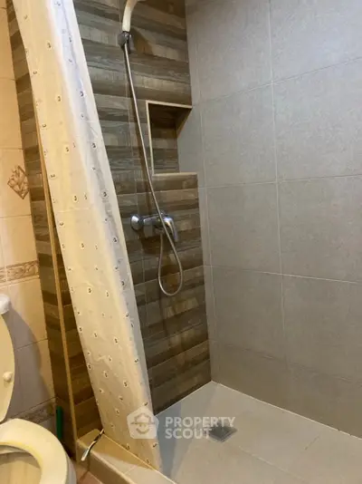 Modern bathroom with tiled shower and curtain, featuring neutral tones.