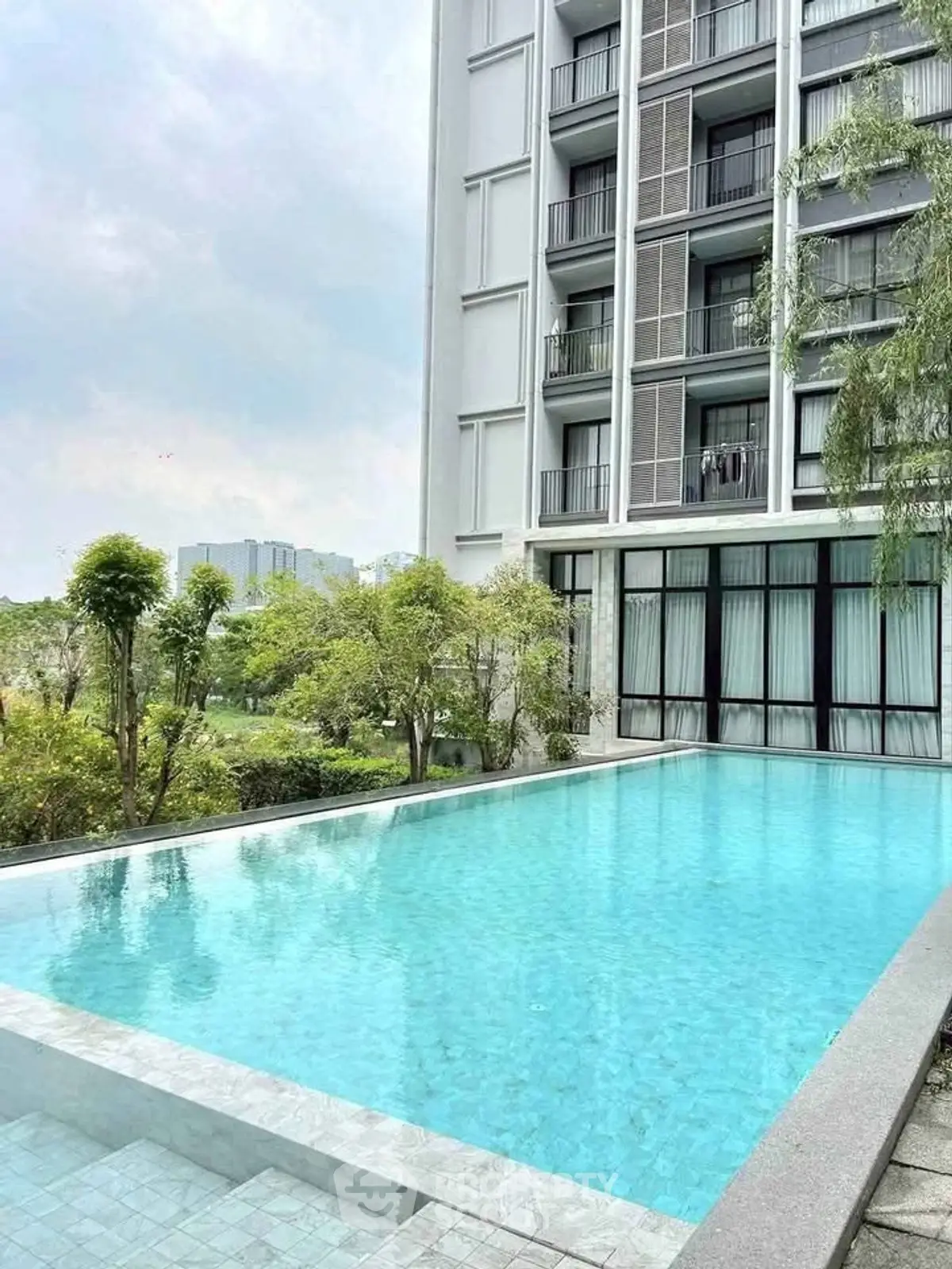 Luxurious apartment building with a stunning outdoor pool and lush greenery.