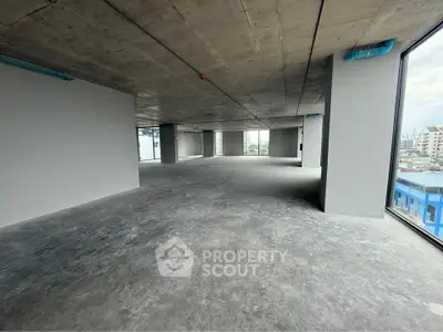 Spacious open-plan commercial space with large windows and concrete flooring, ideal for customization.