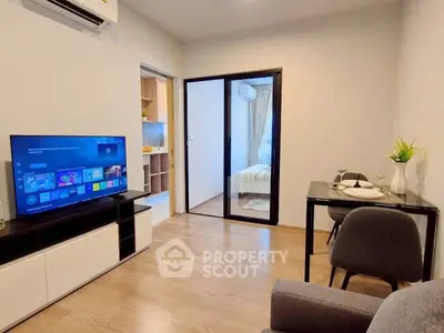 Modern living room with TV, dining area, and view into bedroom, featuring sleek design and cozy ambiance.
