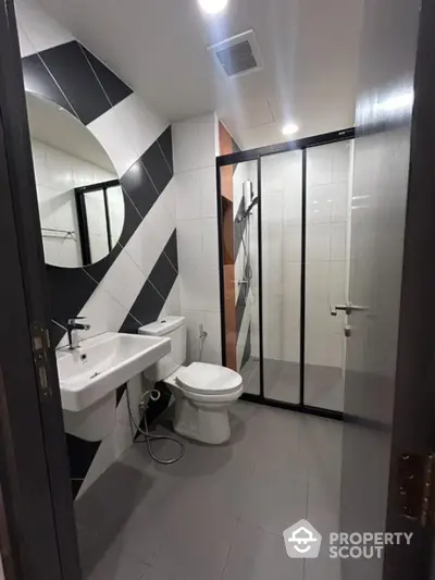 Modern bathroom with stylish black and white tiles and glass shower enclosure