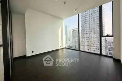 Spacious modern room with floor-to-ceiling windows offering stunning city views in a high-rise building.