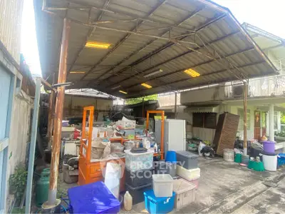 Spacious outdoor storage area with metal roof and various containers, ideal for organizing tools and equipment.