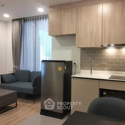Modern apartment interior with sleek kitchen and cozy living area, featuring stylish cabinetry and contemporary furniture.