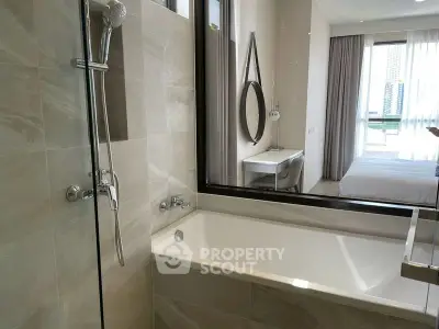 Modern bathroom with bathtub and view into a stylish bedroom, featuring elegant decor and natural light.