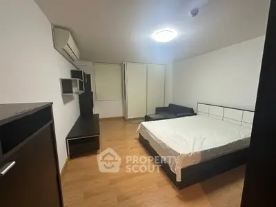 Spacious bedroom with modern furnishings and wooden flooring, featuring a comfortable bed and ample storage.