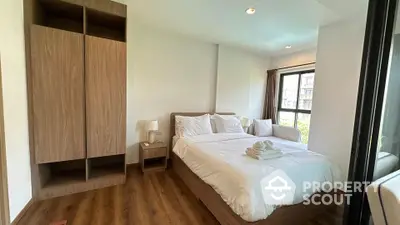 Modern bedroom with wooden flooring and large window offering natural light.