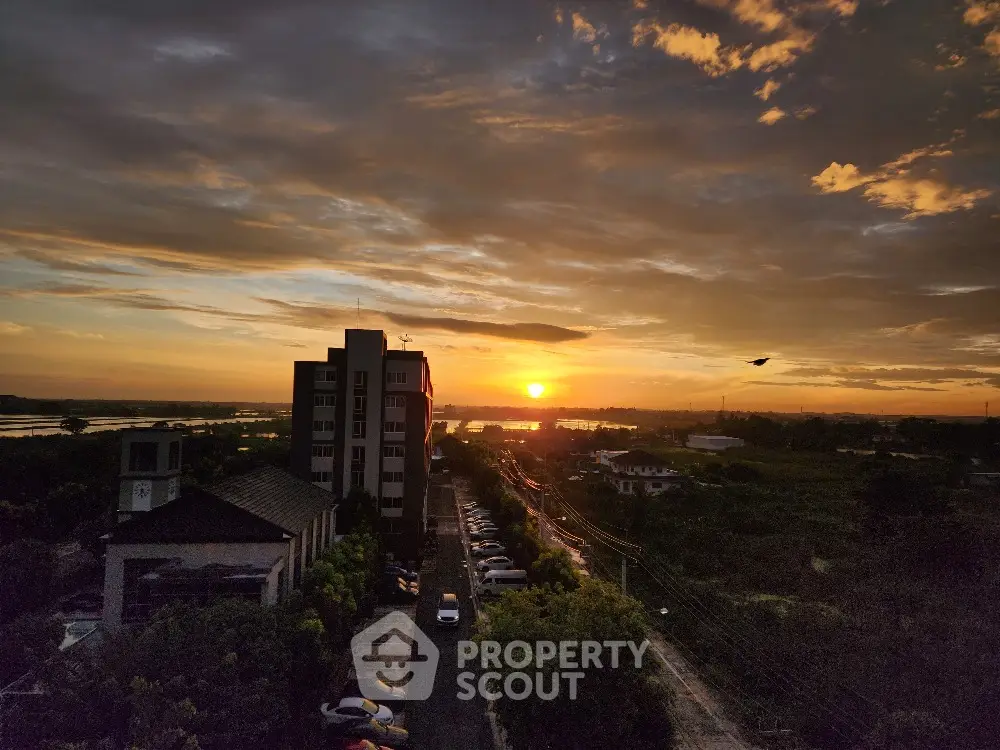 Stunning sunset view from high-rise building overlooking serene landscape and river.