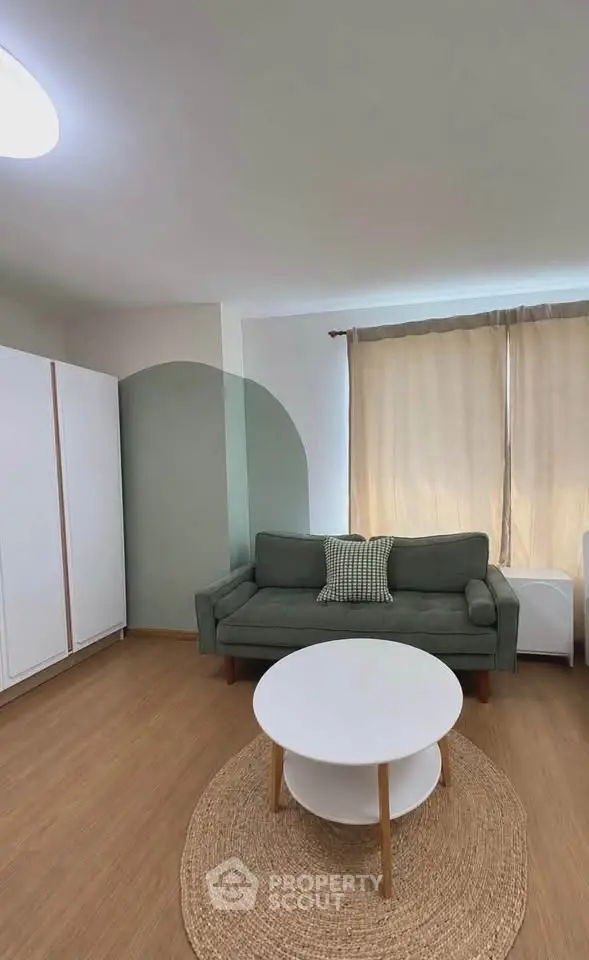 Charming living room with modern sofa, round coffee table, and natural light through large window.