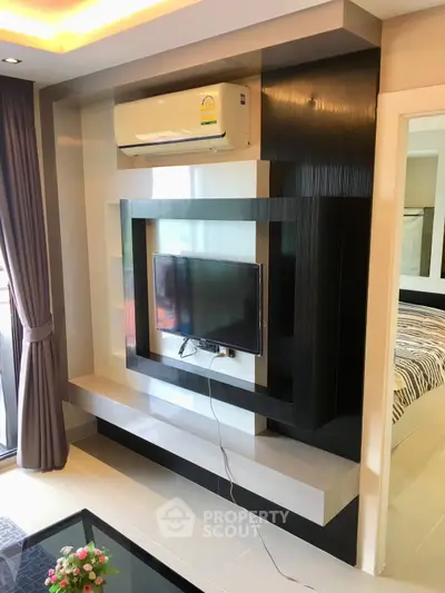 Modern living room with sleek TV wall unit and air conditioning, featuring elegant decor and natural light.