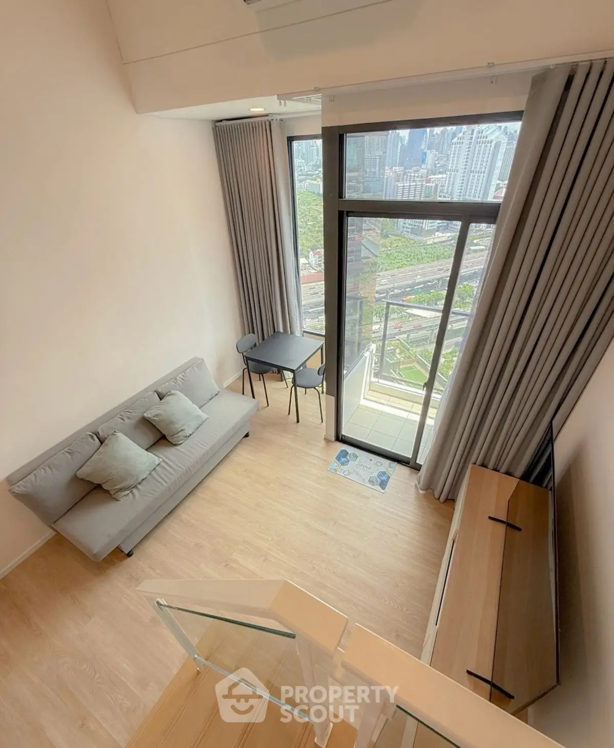 Modern high-rise apartment with balcony and stunning city view, featuring sleek interior design and cozy living space.