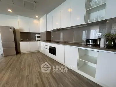 Modern kitchen with sleek white cabinets and stainless steel appliances in a spacious open layout.