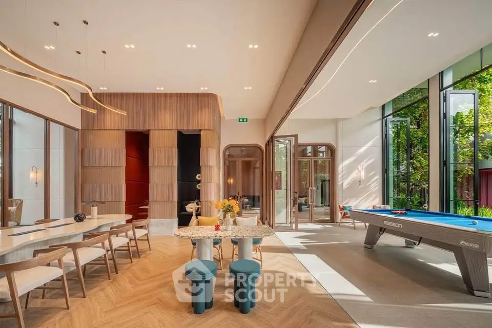 Luxurious modern living room with pool table and elegant dining area, featuring floor-to-ceiling windows and stylish decor.