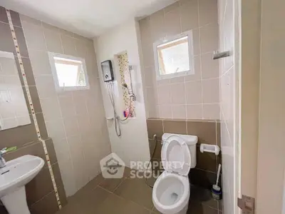 Modern bathroom with tiled walls, shower, and toilet in a bright, airy space.