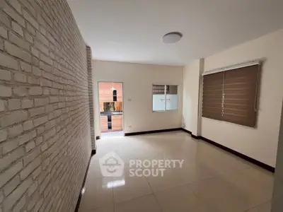 Spacious living room with modern brick accent wall and large window for natural light.