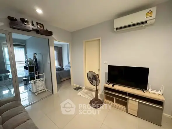 Modern living room with air conditioning and TV, adjacent to a cozy bedroom.