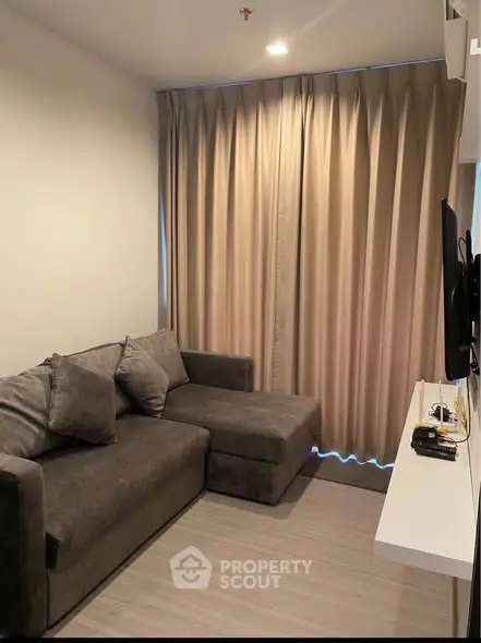 Cozy living room with modern gray sofa and wall-mounted TV, perfect for relaxation.