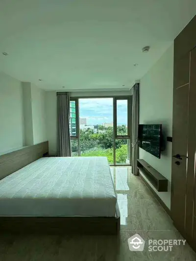 Spacious bedroom with large window offering stunning city view and modern minimalist design.