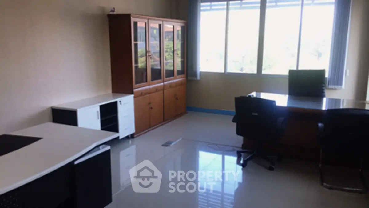 Spacious office room with large window and modern furniture, ideal for productivity and comfort.