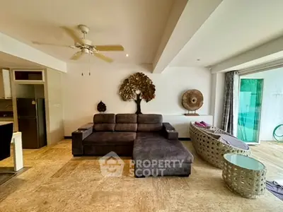 Spacious living room with modern decor and large sofa, opening to a balcony with natural light.