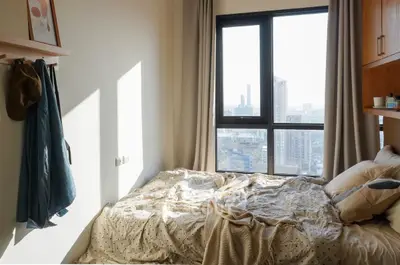 Cozy bedroom with city view and natural light, perfect for urban living.