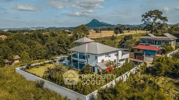 Stunning aerial view of a luxurious villa with pool and lush garden, nestled in serene countryside setting.