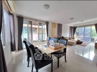 Spacious living room with dining area and large windows offering garden views.