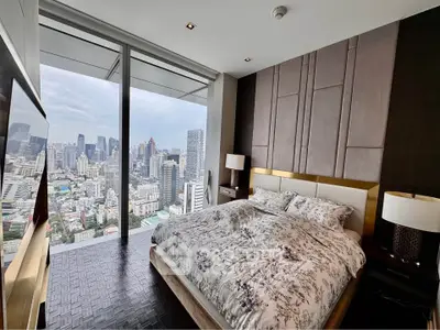 Luxurious bedroom with stunning city view from floor-to-ceiling windows in high-rise apartment.